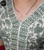 Elevate your ethnic wardrobe with this stunning full-length kurti dress in a sophisticated green and white floral print. The dress features exquisite white lace detailing along the V-neckline, creating an elegant contrast against the verdant floral pattern. The full-length silhouette offers graceful movement, while the long sleeves with gathered cuffs add a touch of vintage charm. The traditional design is beautifully modernised with intricate geometric patterns adorning the neckline and hem. Crafted with attention to detail, this kurti dress combines comfort with style, making it perfect for festive occasions or formal events. The white base with sage green floral motifs creates a fresh, timeless appeal. The dress includes delicate embellishments and can be paired with matching bottoms for a complete ensemble. The flowing silhouette ensures comfort throughout the day while maintaining a sophisticated appearance.
